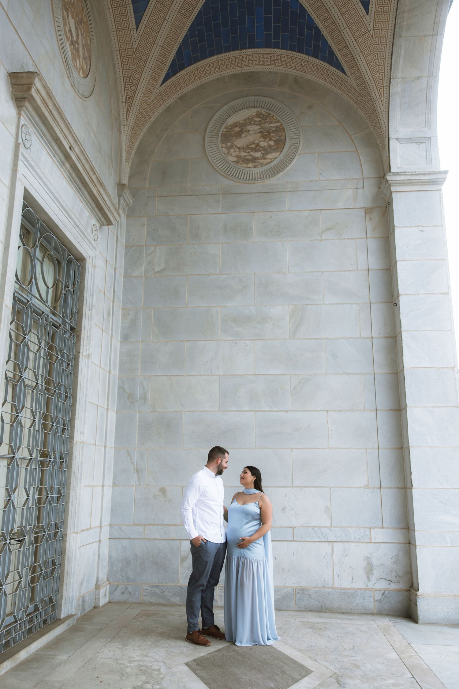 Couple in formal wear posing under elegant stone archways.