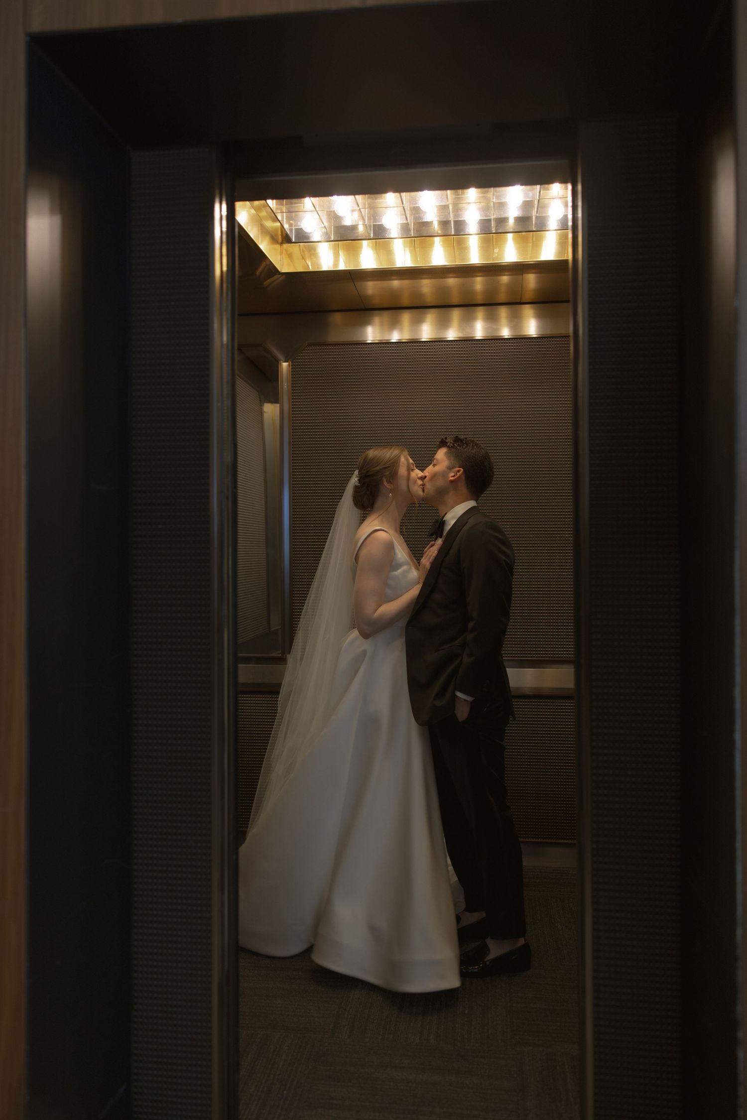 Romantic elevator moment between bride and groom on their wedding day.