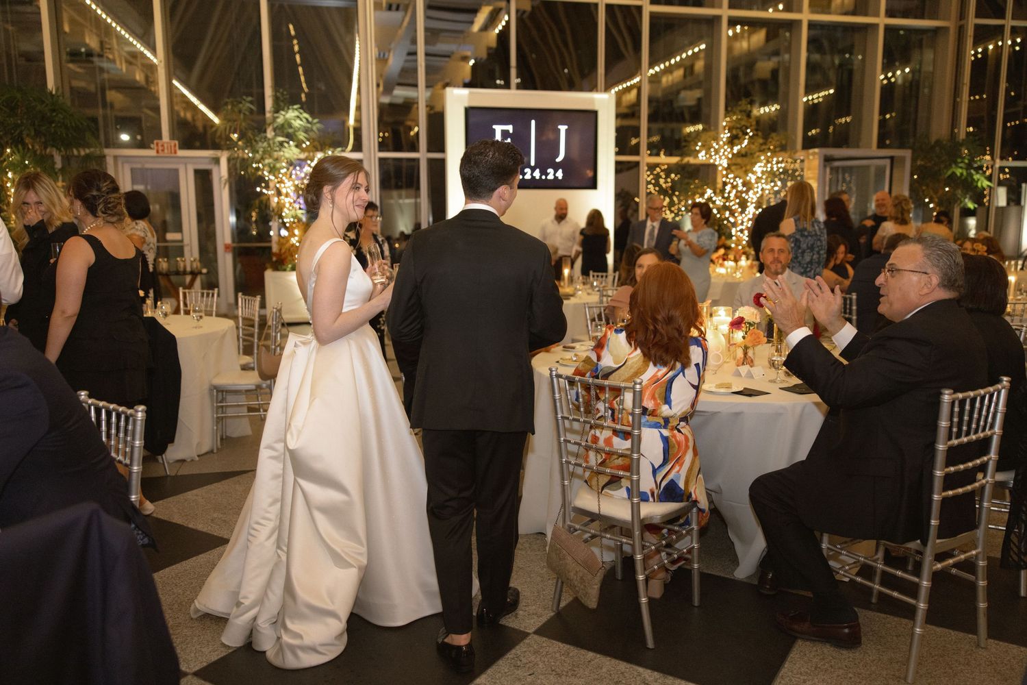 Wedding reception celebration with guests dining in an industrial-chic venue with string lights.