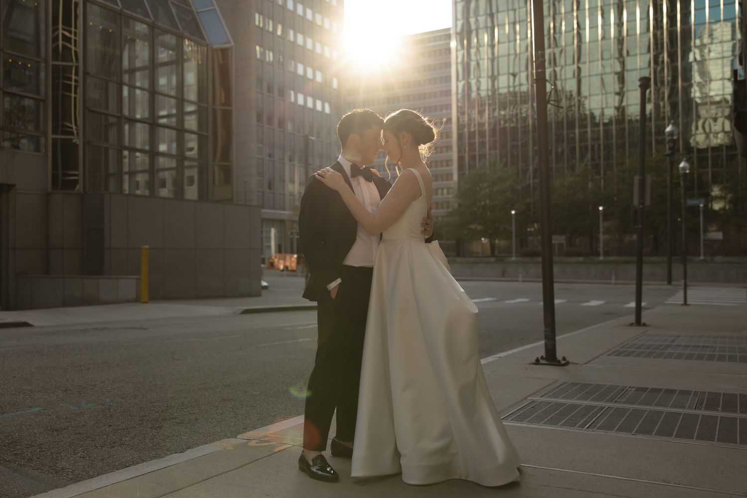 Romantic sunset portrait of newlyweds embracing in downtown city setting.