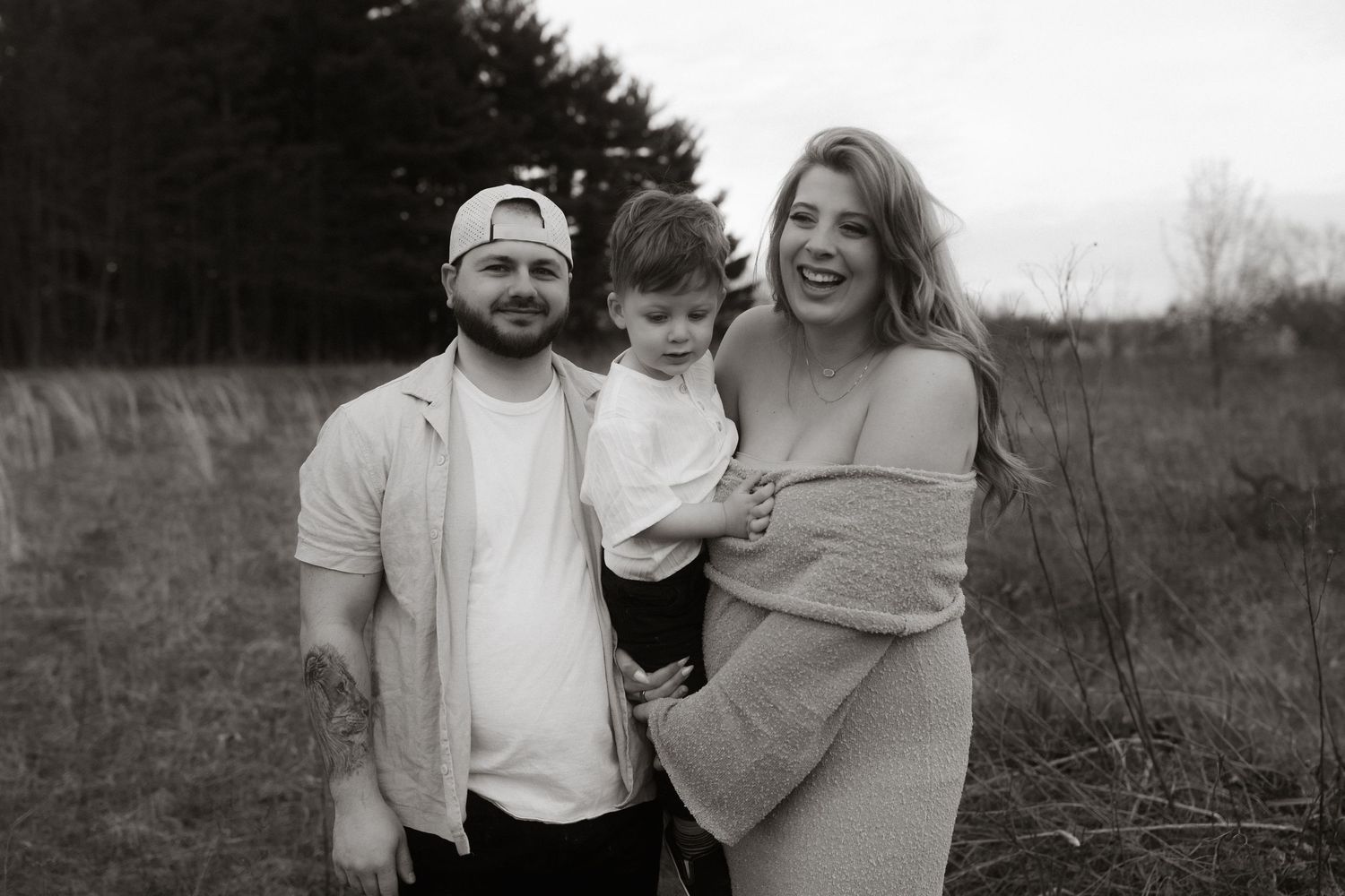 Family portrait in black and white against natural outdoor backdrop.