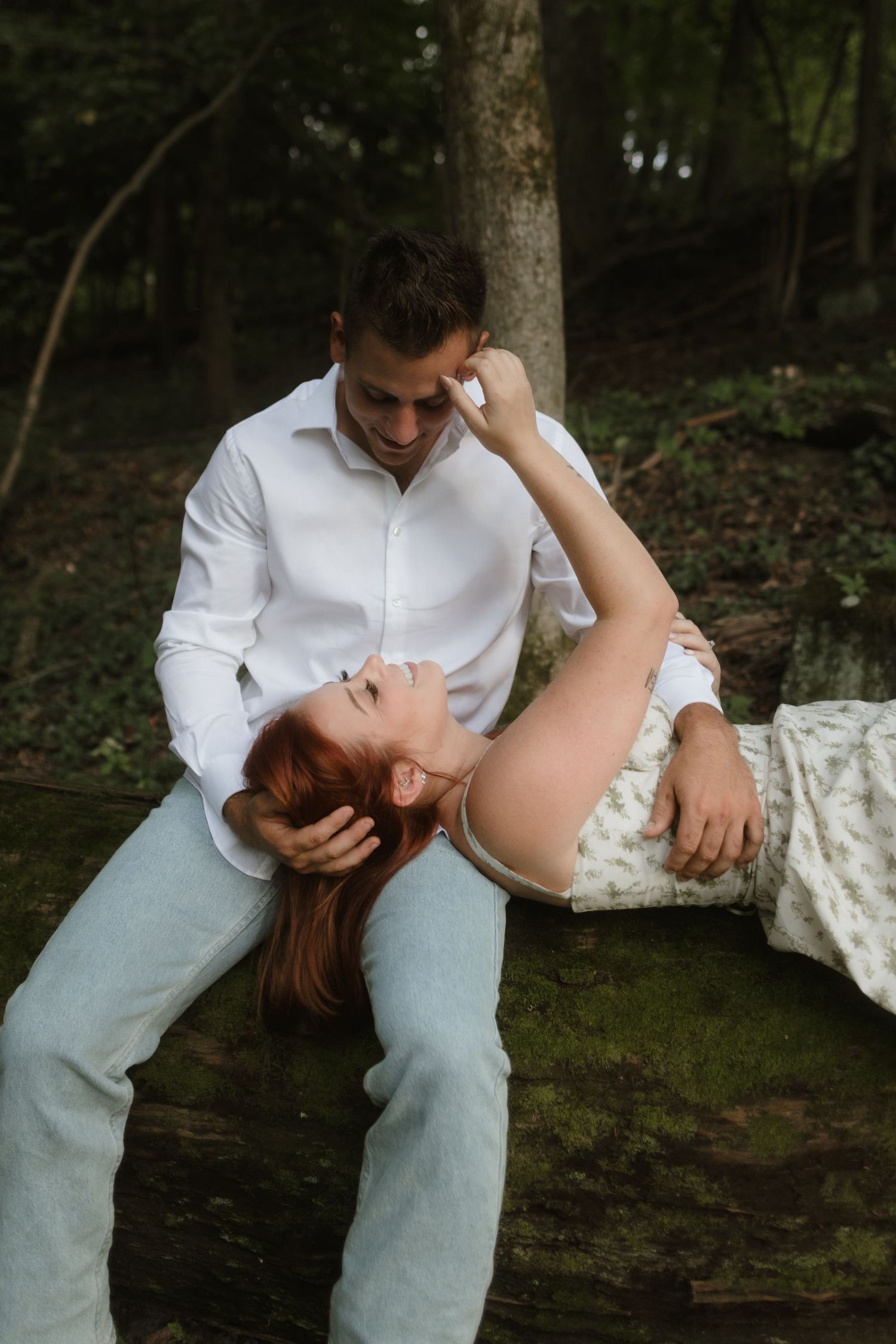 A romantic outdoor portrait of a couple on a fallen log in the woods.