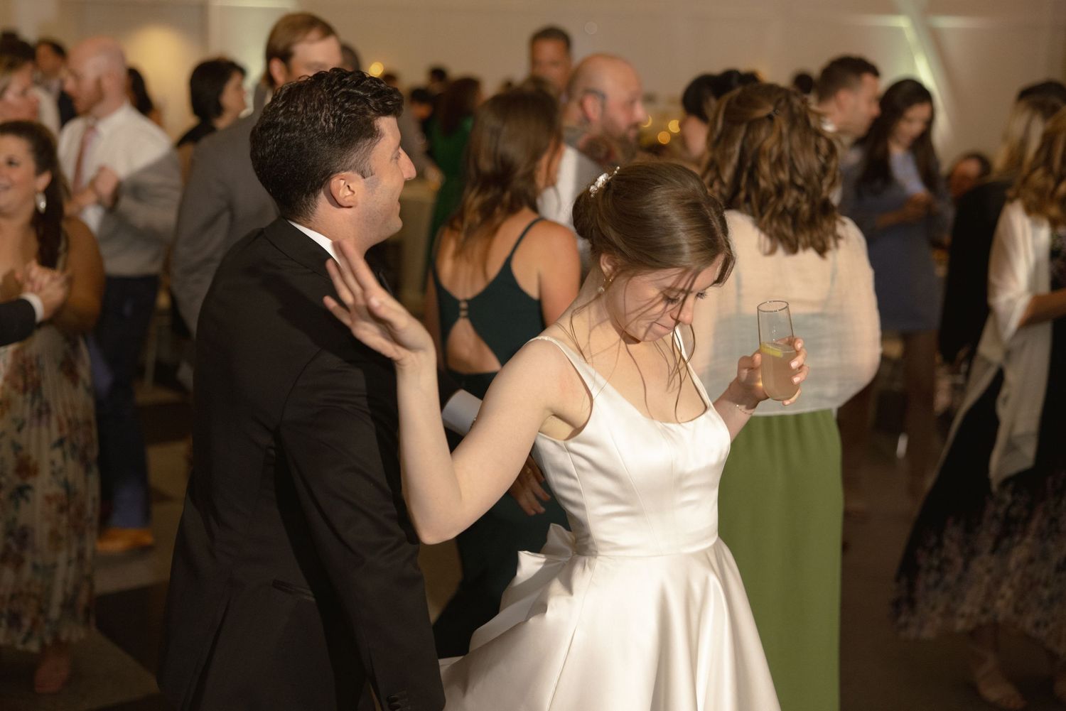 Couple dancing at wedding reception surrounded by guests in elegant venue.