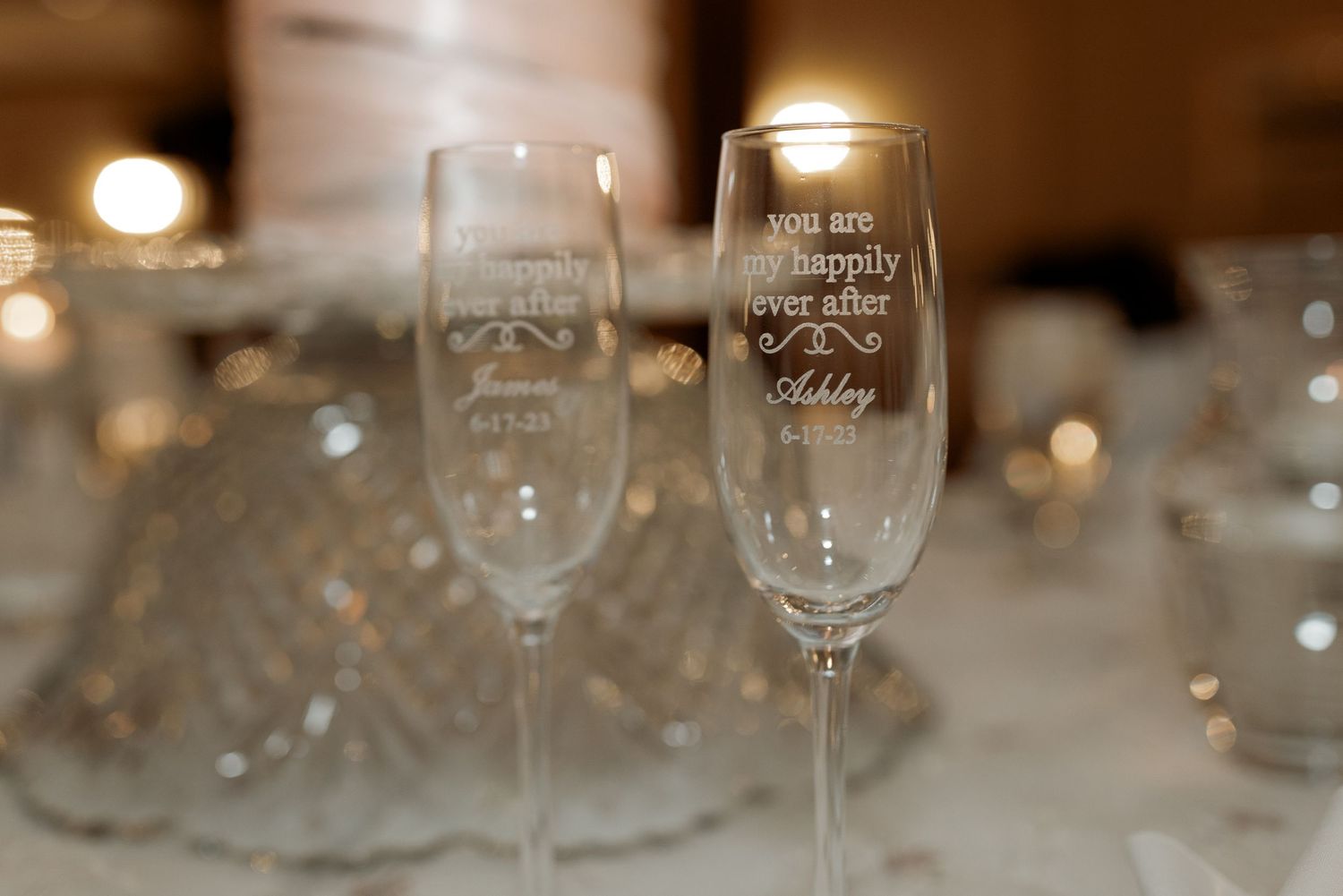 Engraved champagne flutes for bride and groom on elegant wedding reception table.
