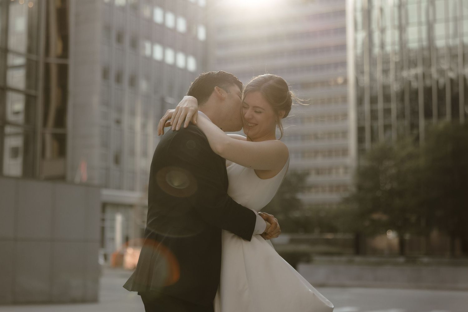Couple sharing romantic embrace during golden hour in city setting.
