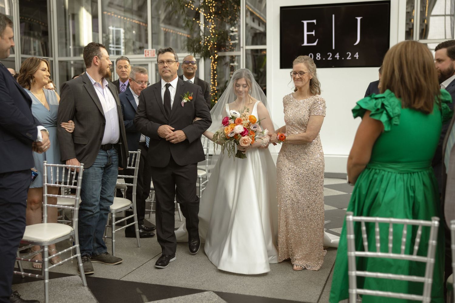 Wedding ceremony in modern venue with floral arrangements and chiavari chairs.