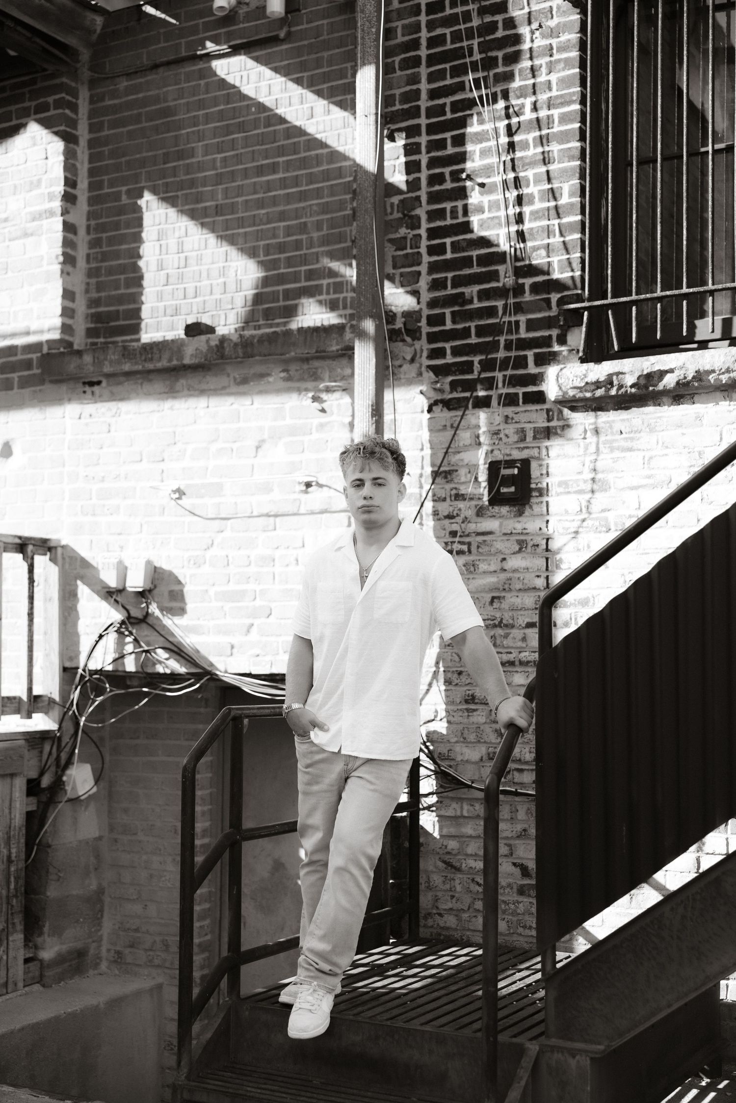 Black and white photograph on a stairwell with brick walls showing a casual industrial urban setting.