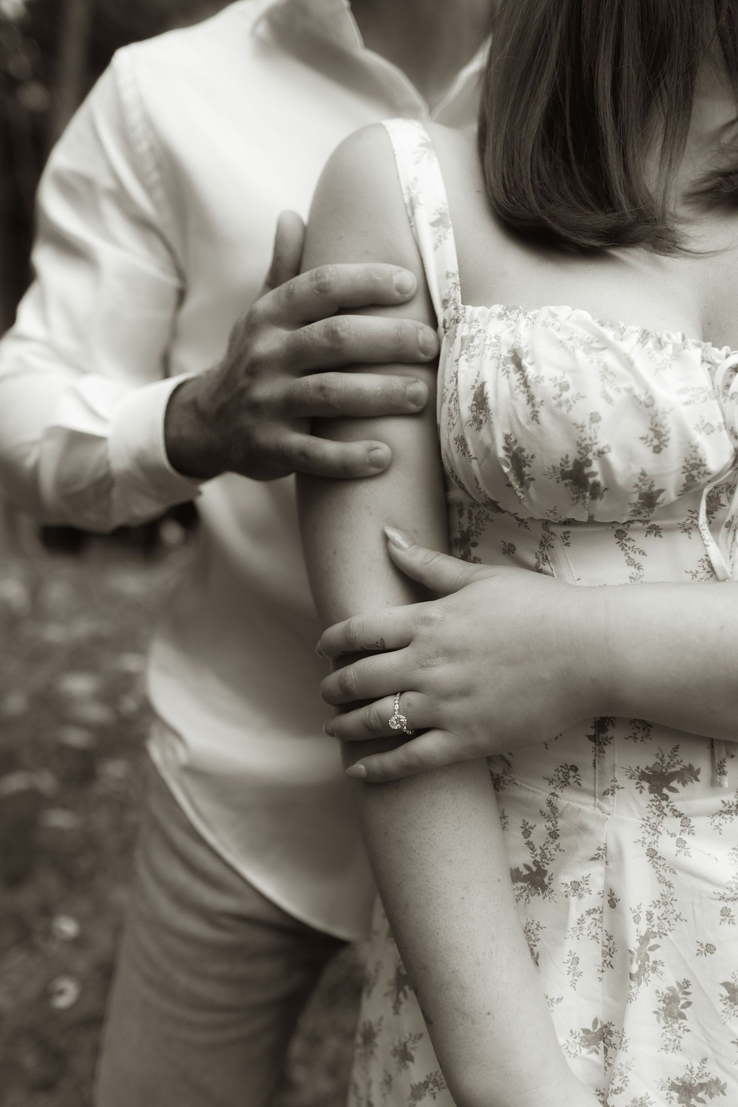 Close up black and white photo showing hands and embrace of couple in romantic wedding attire.