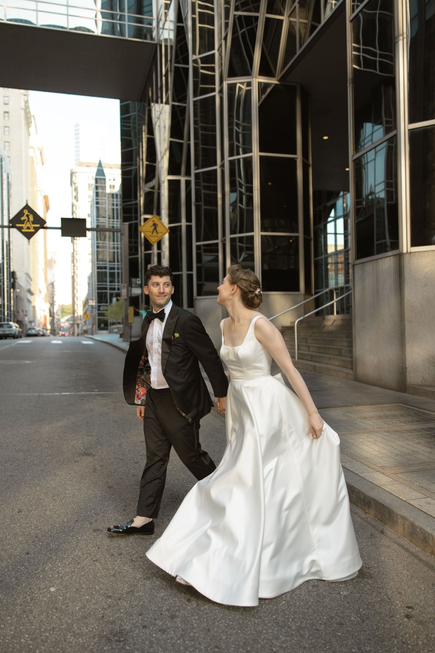 Wedding couple walking together outside urban building with glass architecture.