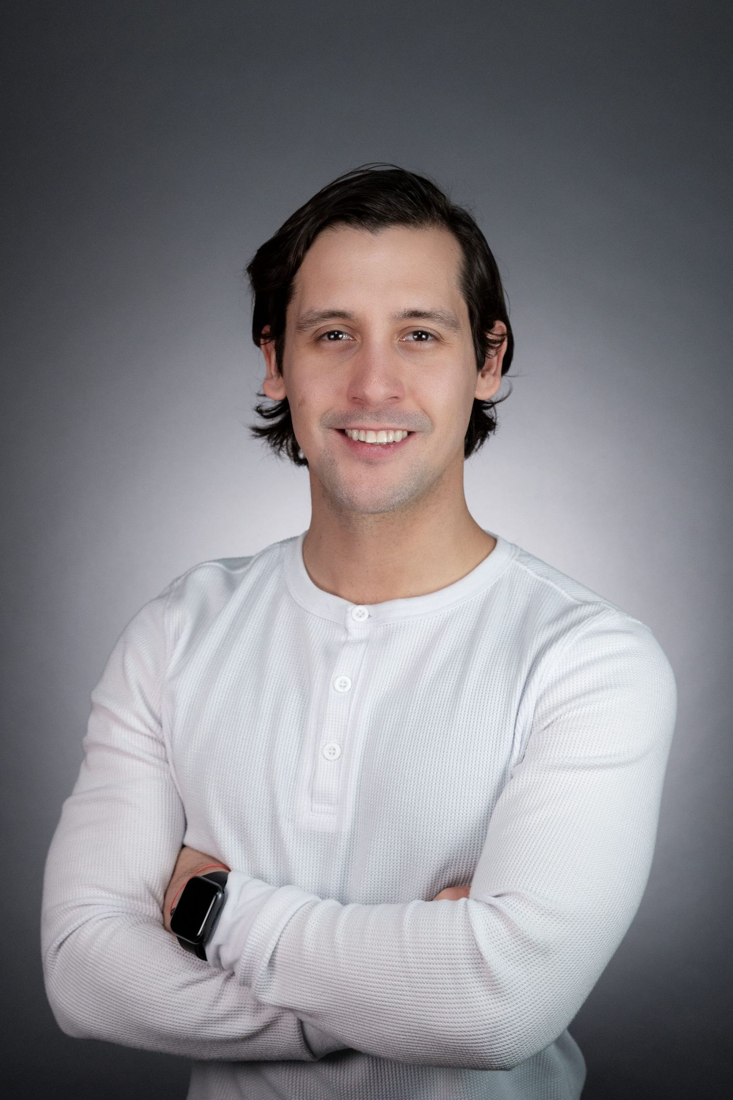 Professional headshot of a man in white henley against a gray background.