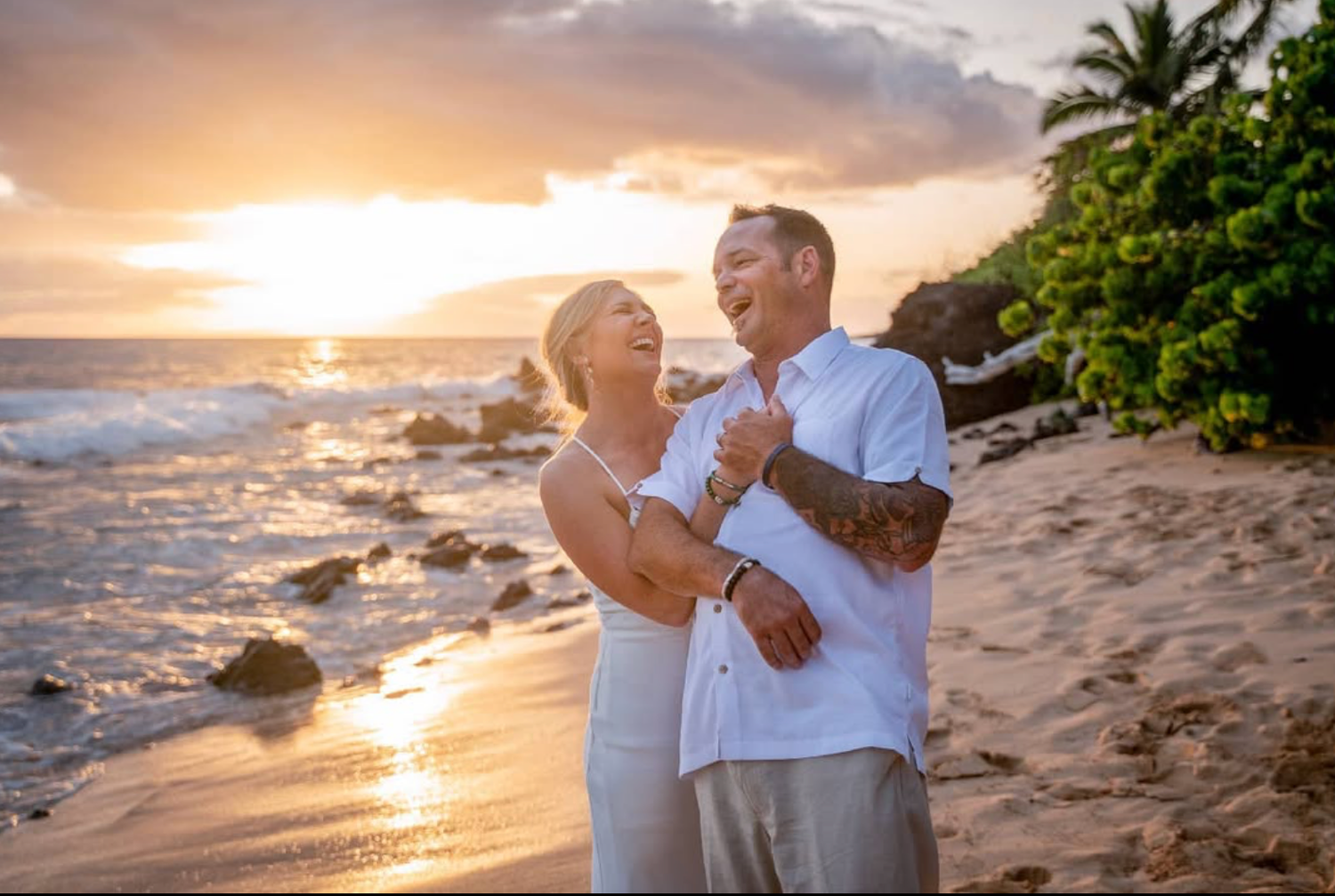 Couple dancing on a tropical beach at sunset with palm trees and ocean waves.
