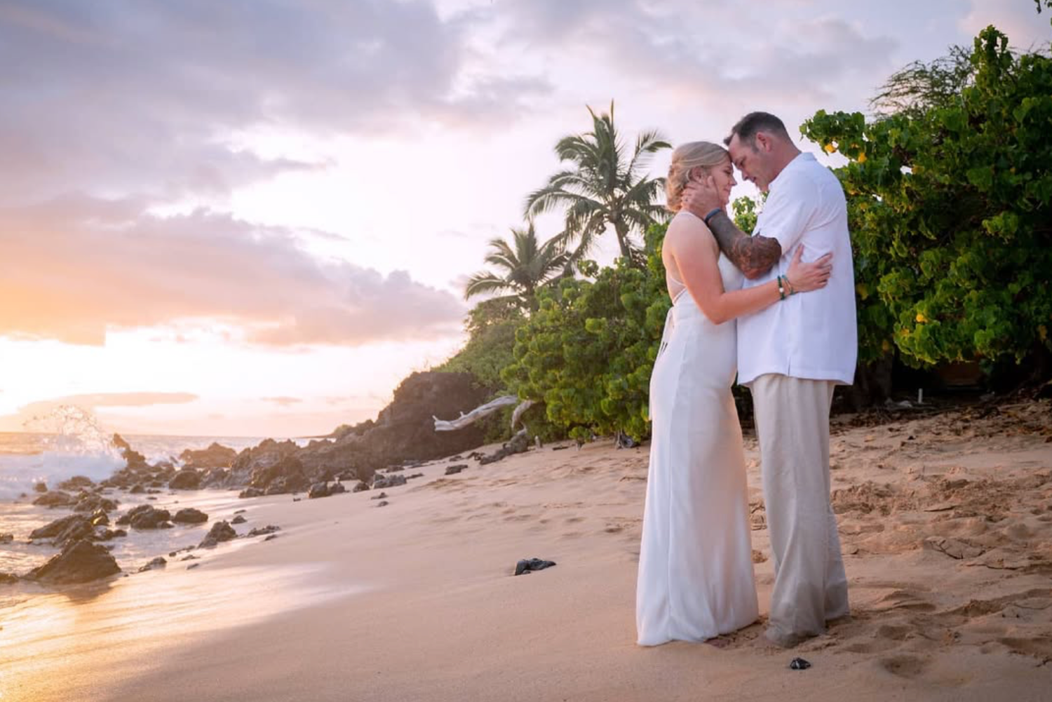 Romantic beach wedding portrait with golden sunset and palm trees in Hawaii.