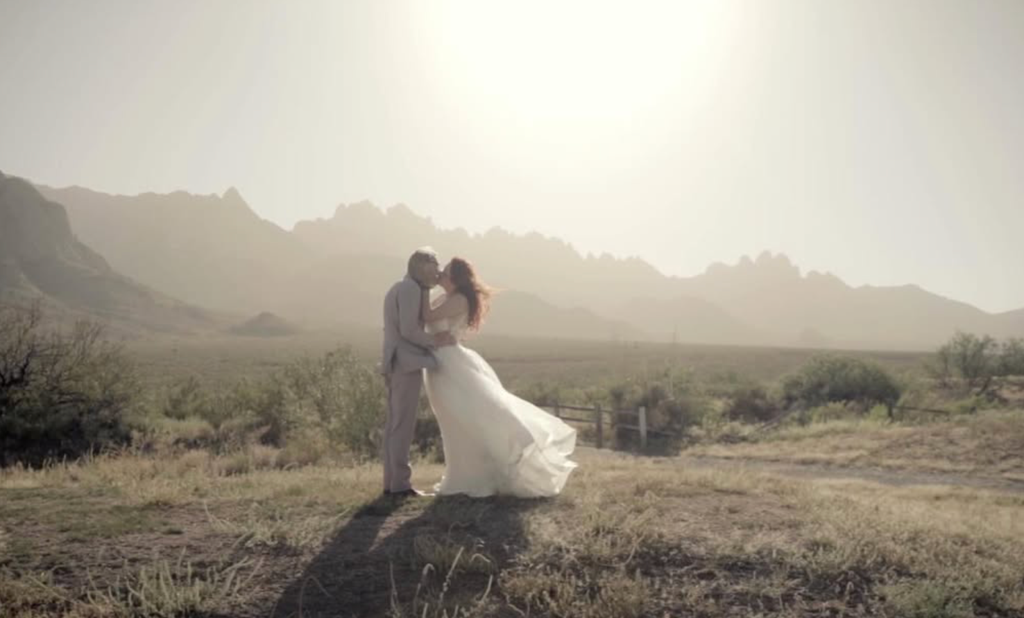 Romantic desert wedding photo with mountain backdrop and dreamy lighting.