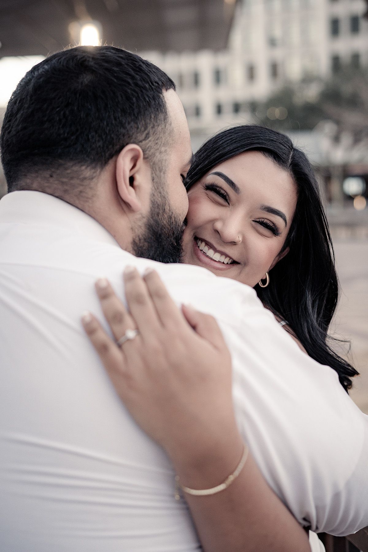 A romantic couple shares an intimate embrace while the woman smiles joyfully.