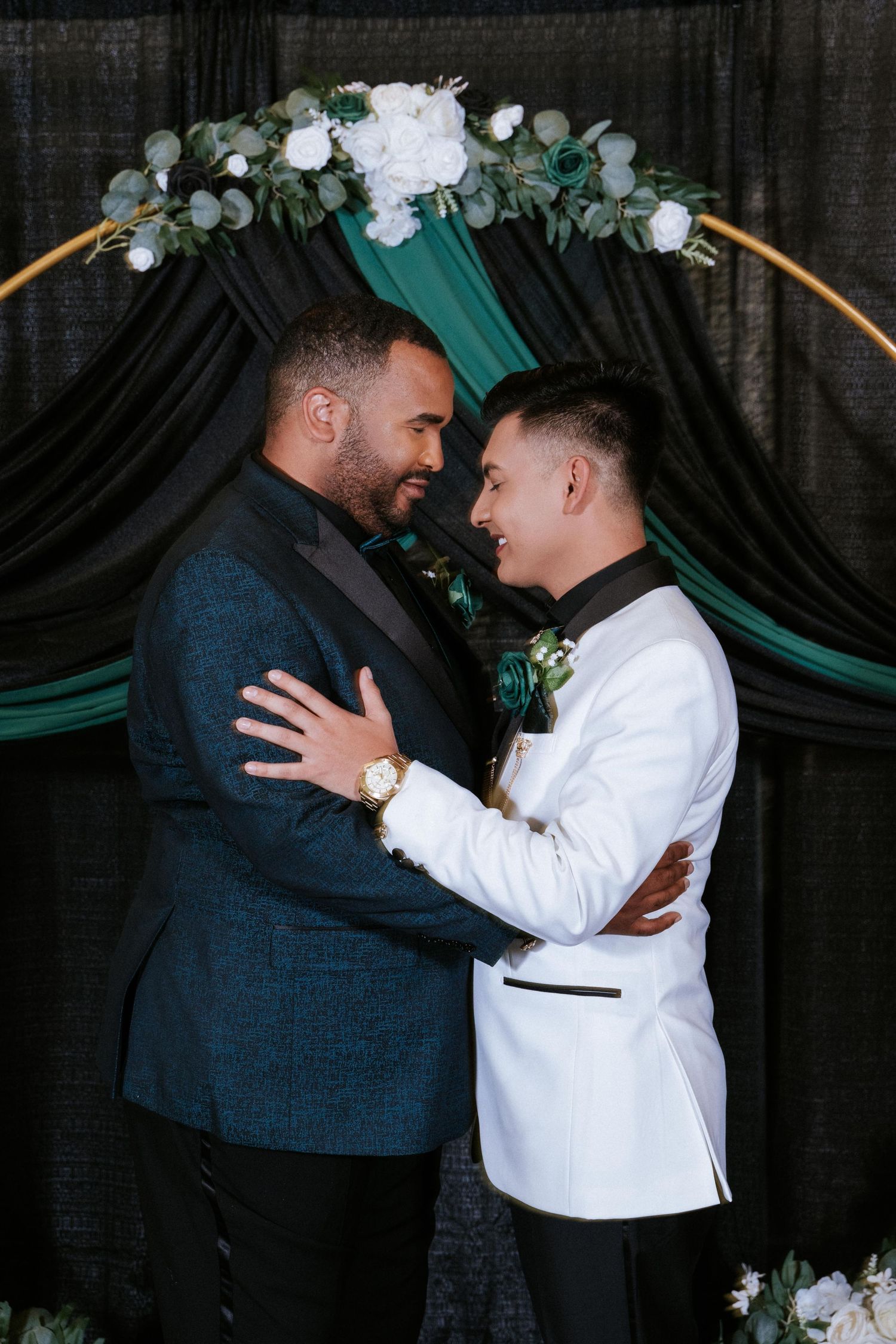 A joyful wedding moment under a green and white floral arch with eucalyptus leaves.