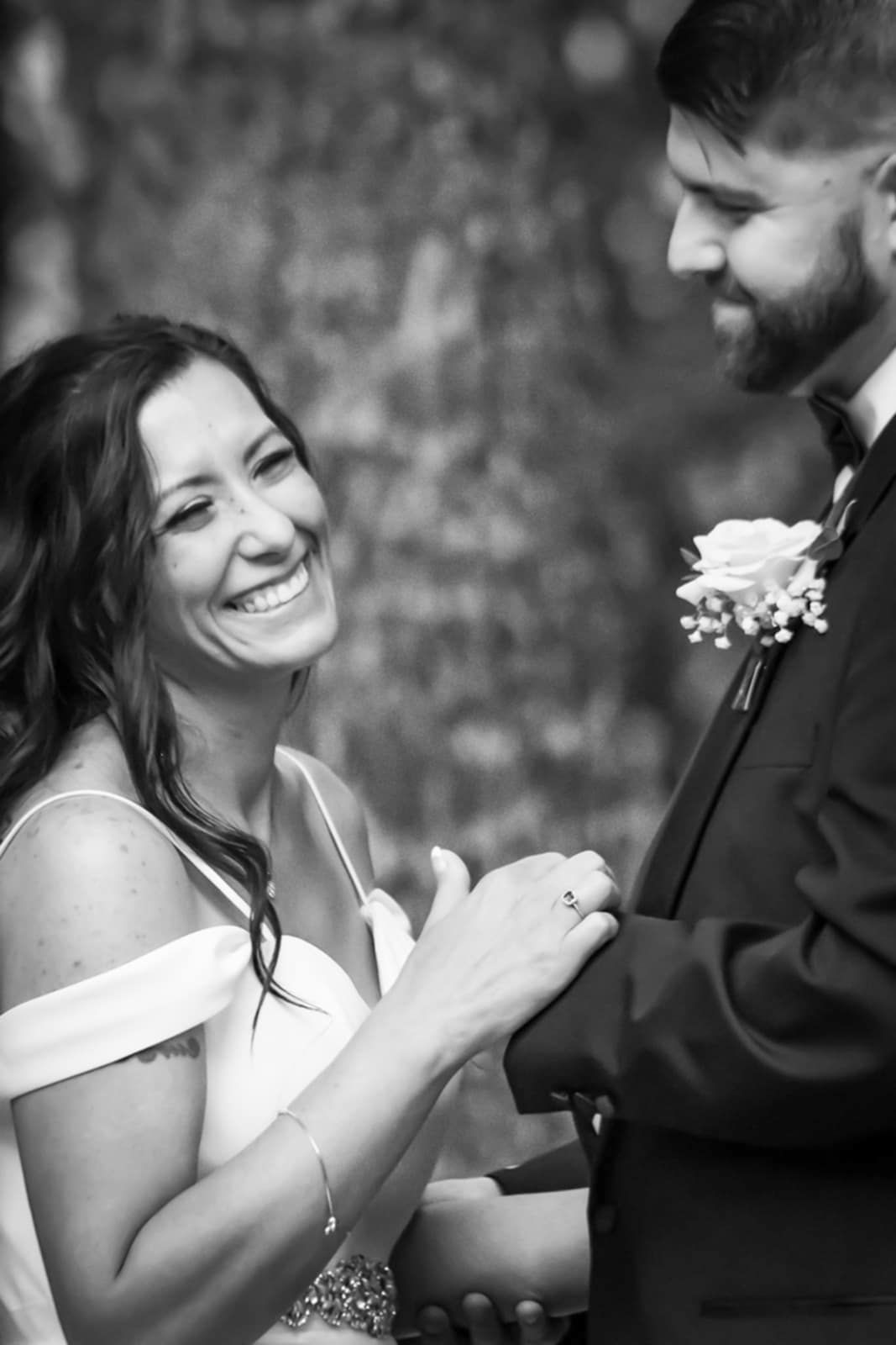 Black and white candid shot showing joyful interaction between two wedding attendees.