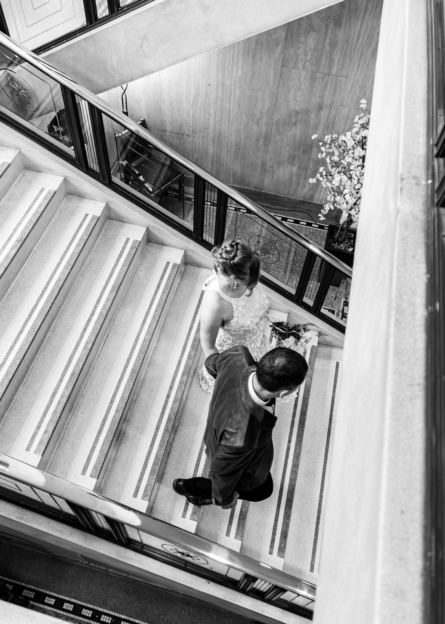 Black and white overhead view of vintage staircase with two people ascending the white steps at iconic angles.