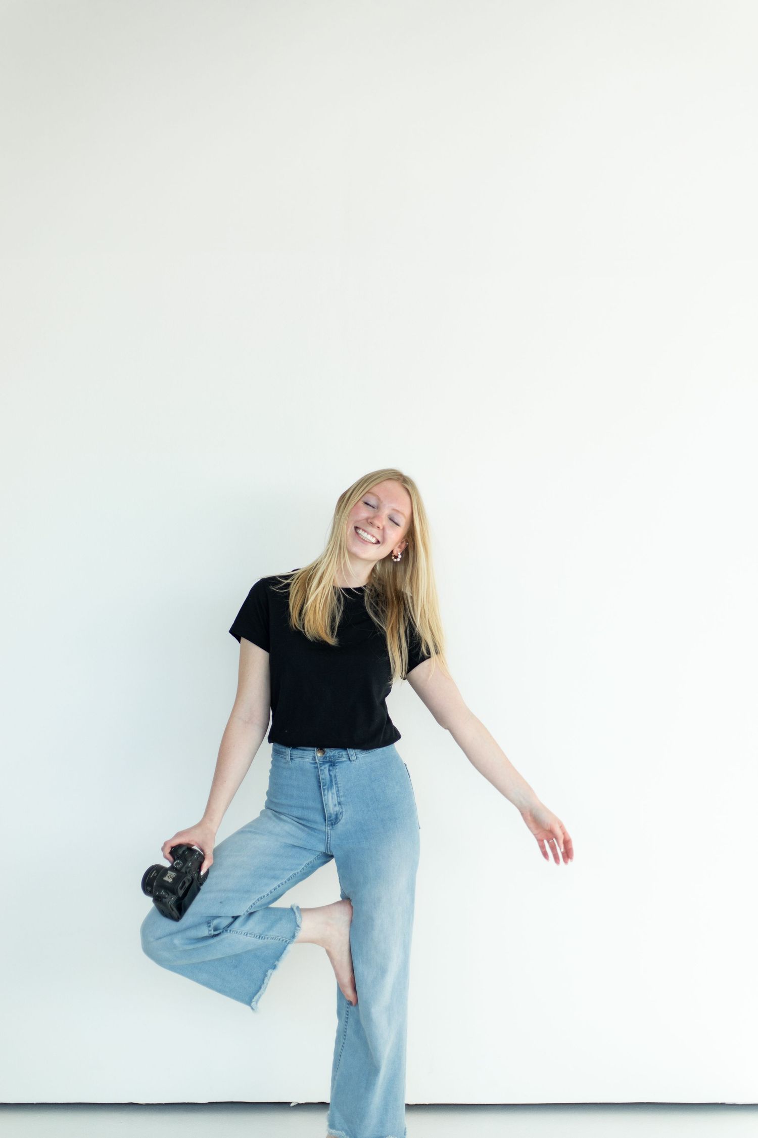 Dynamic photo of photographer in motion against white background holding camera.