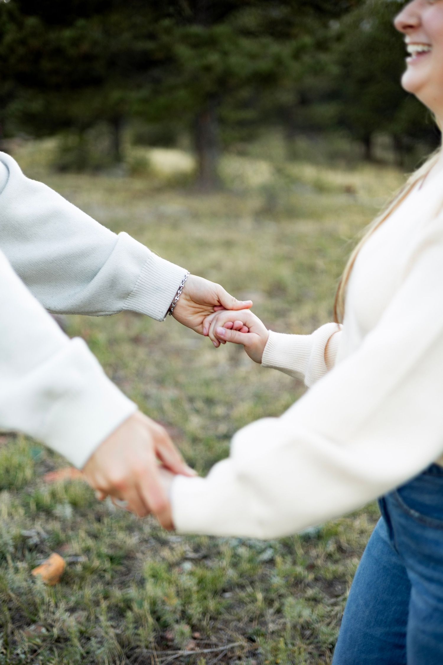 Close-up of hands holding each other gently against a natural outdoor background.