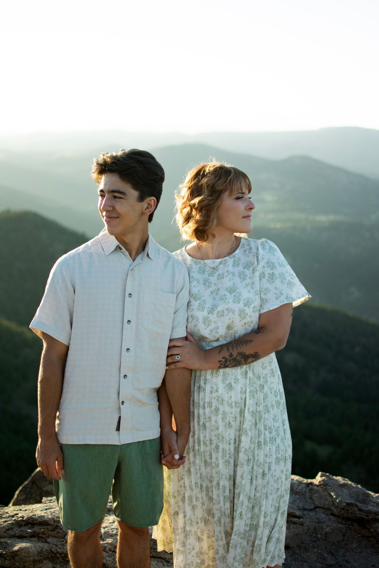 A couple embracing while enjoying a scenic mountain overlook view.