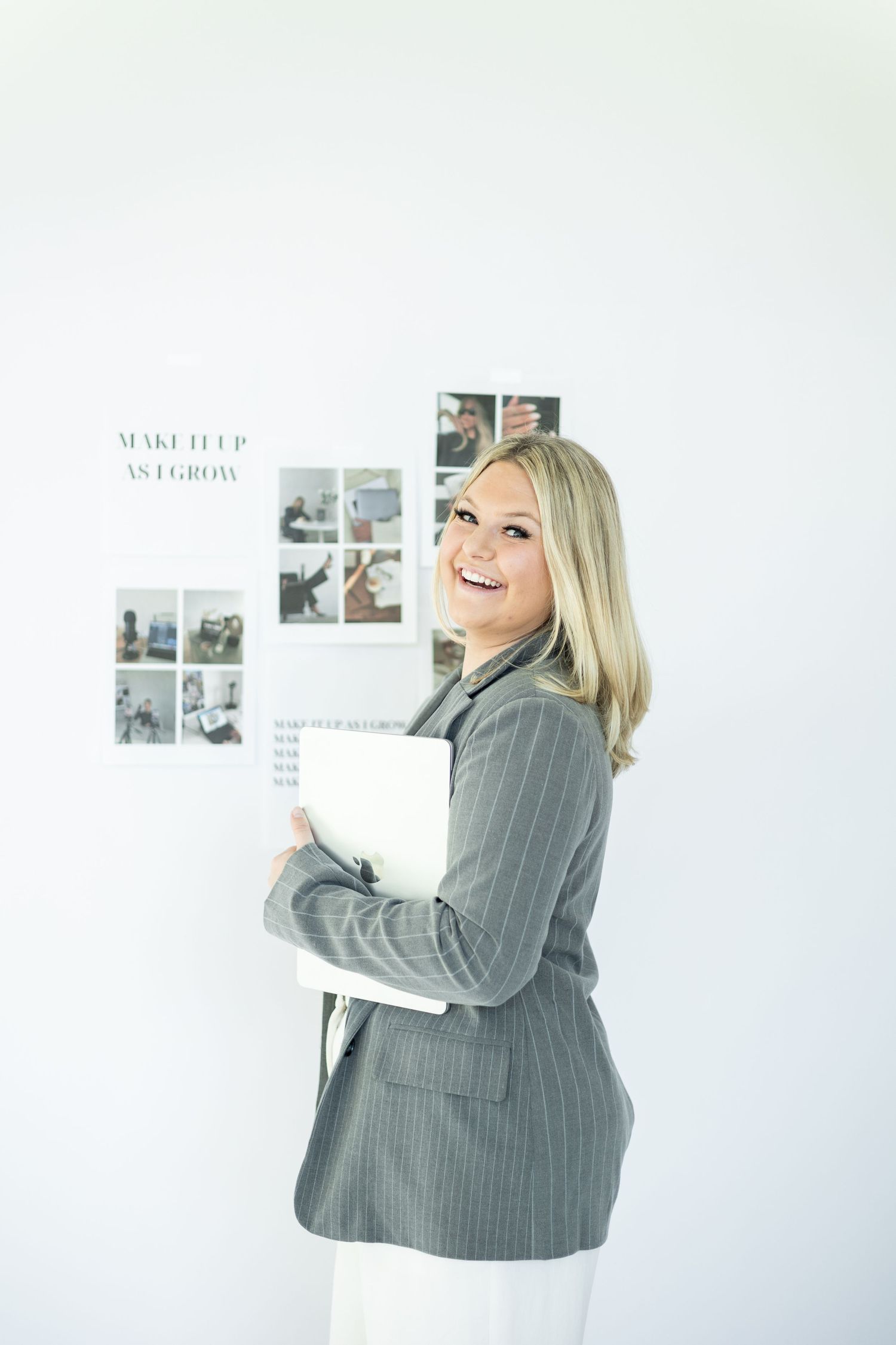 Professional stands near mood board with photos on white wall.