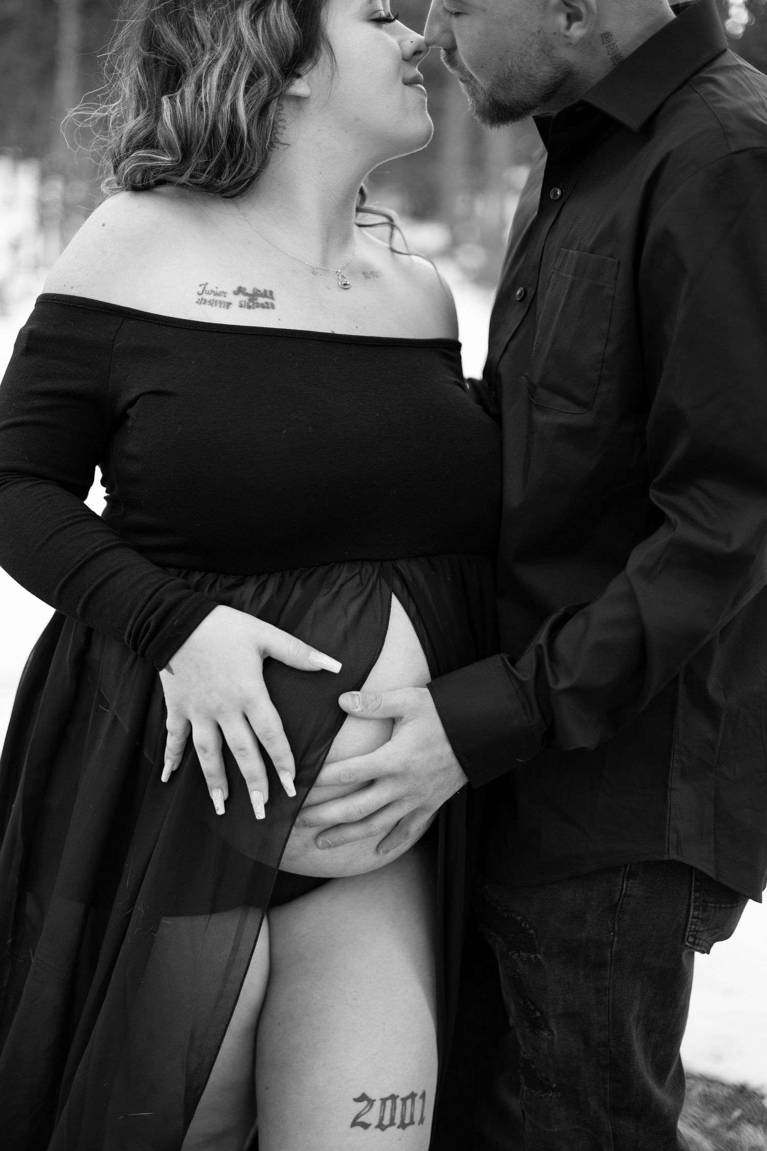Romantic black and white maternity portrait showing an intimate moment between expecting couple outdoors.