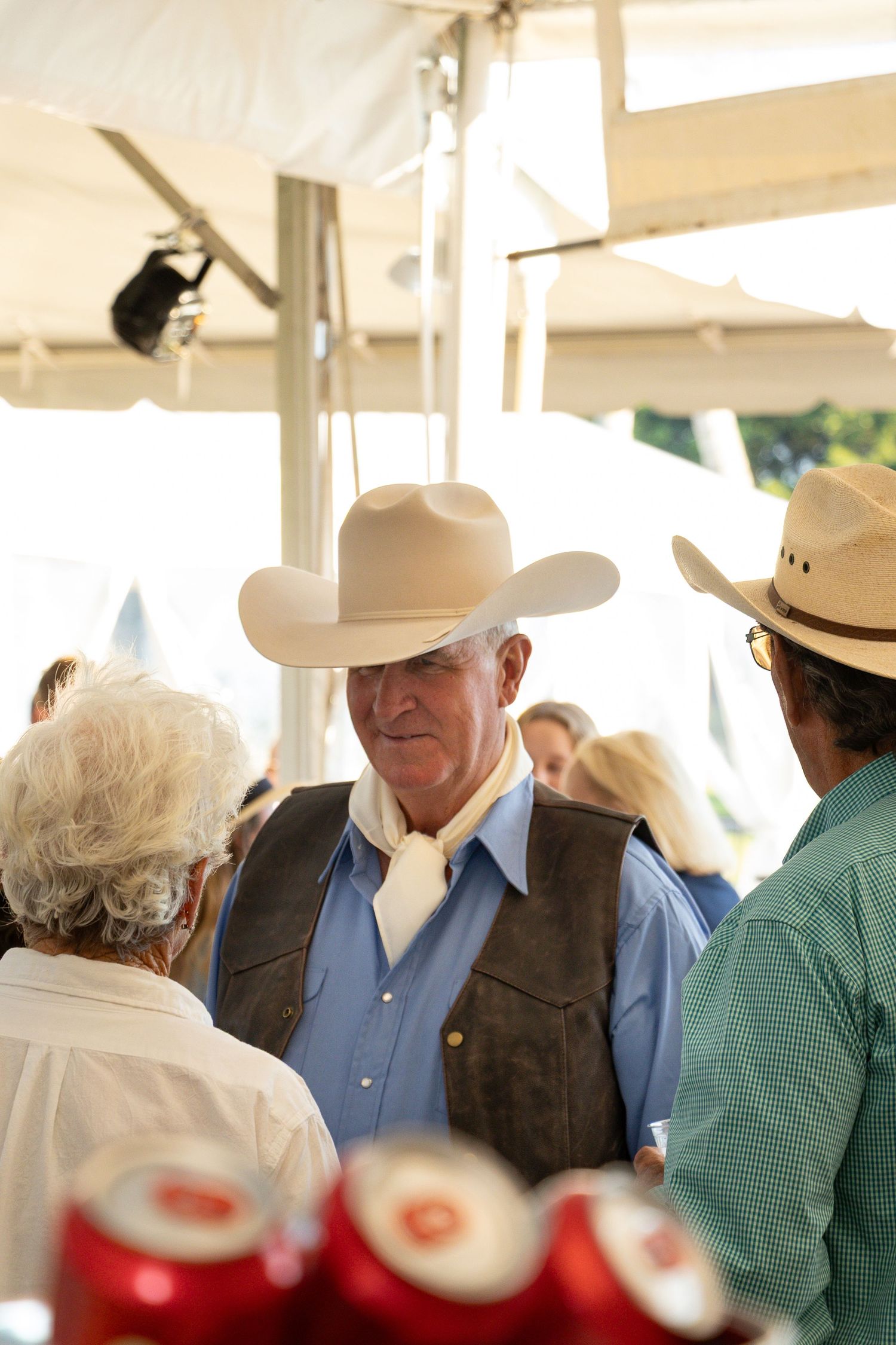 People gathered at a western event with Budweiser cans visible in the foreground.