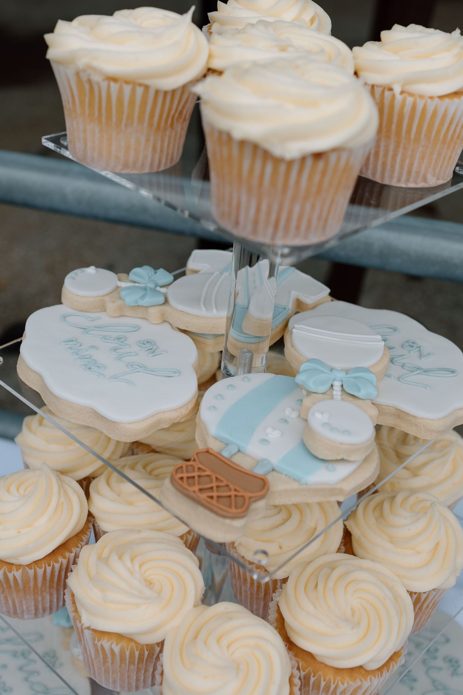 Elegant baby shower dessert display featuring vanilla cupcakes and decorated sugar cookies in soft blue and white.