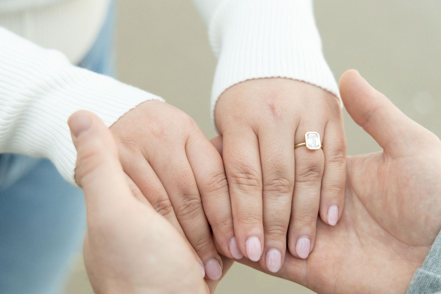 Close-up of hands with engagement ring showing tender moment.