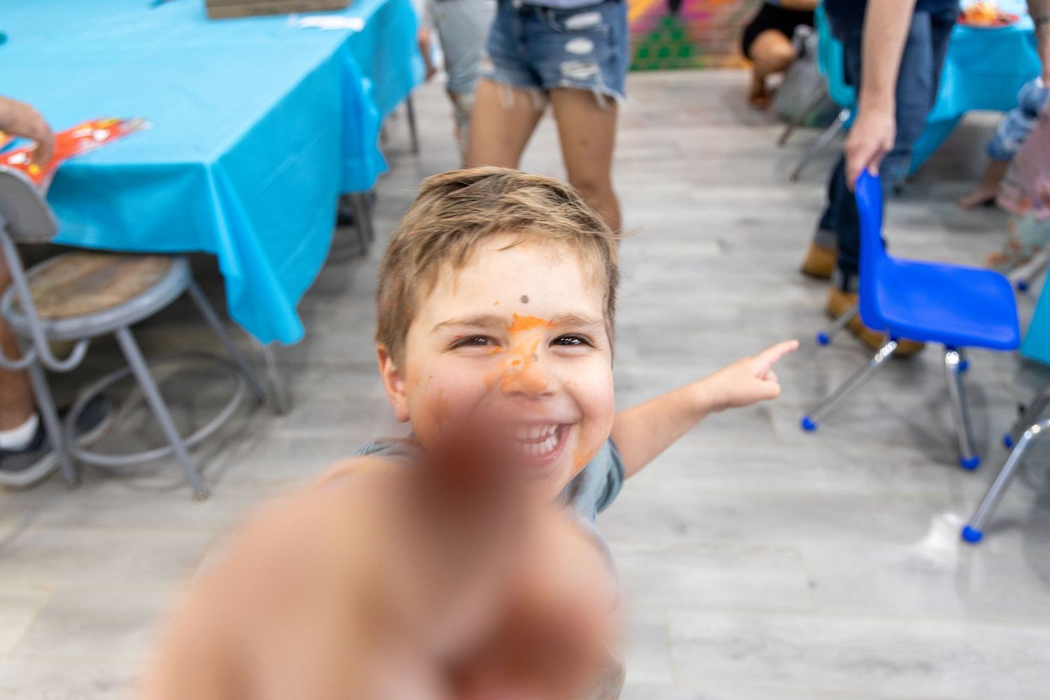A young participant enjoys a festive outdoor event with a painted orange stripe across their face.