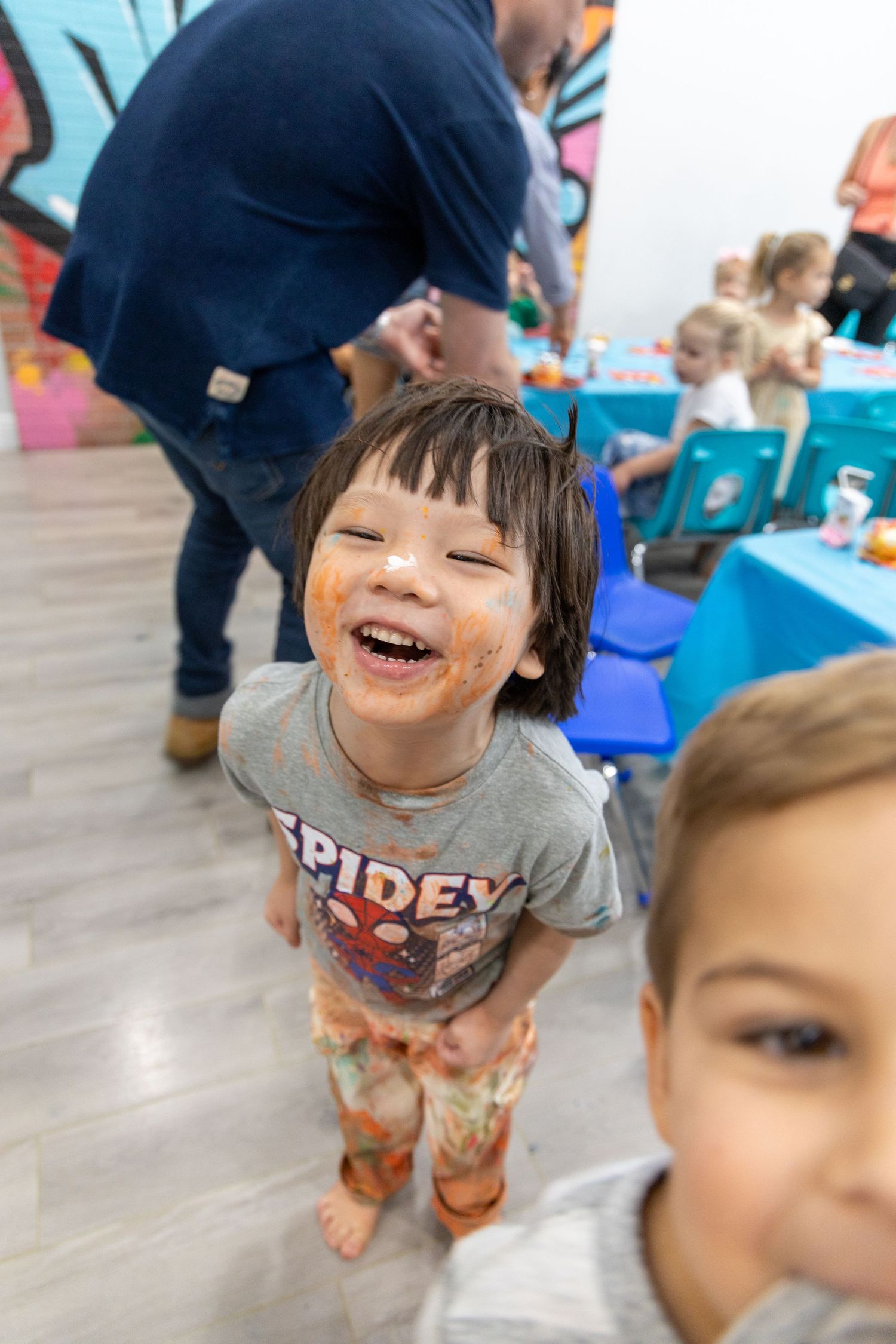 Children playing and laughing during an indoor activity with colorful decor at a party or educational setting.