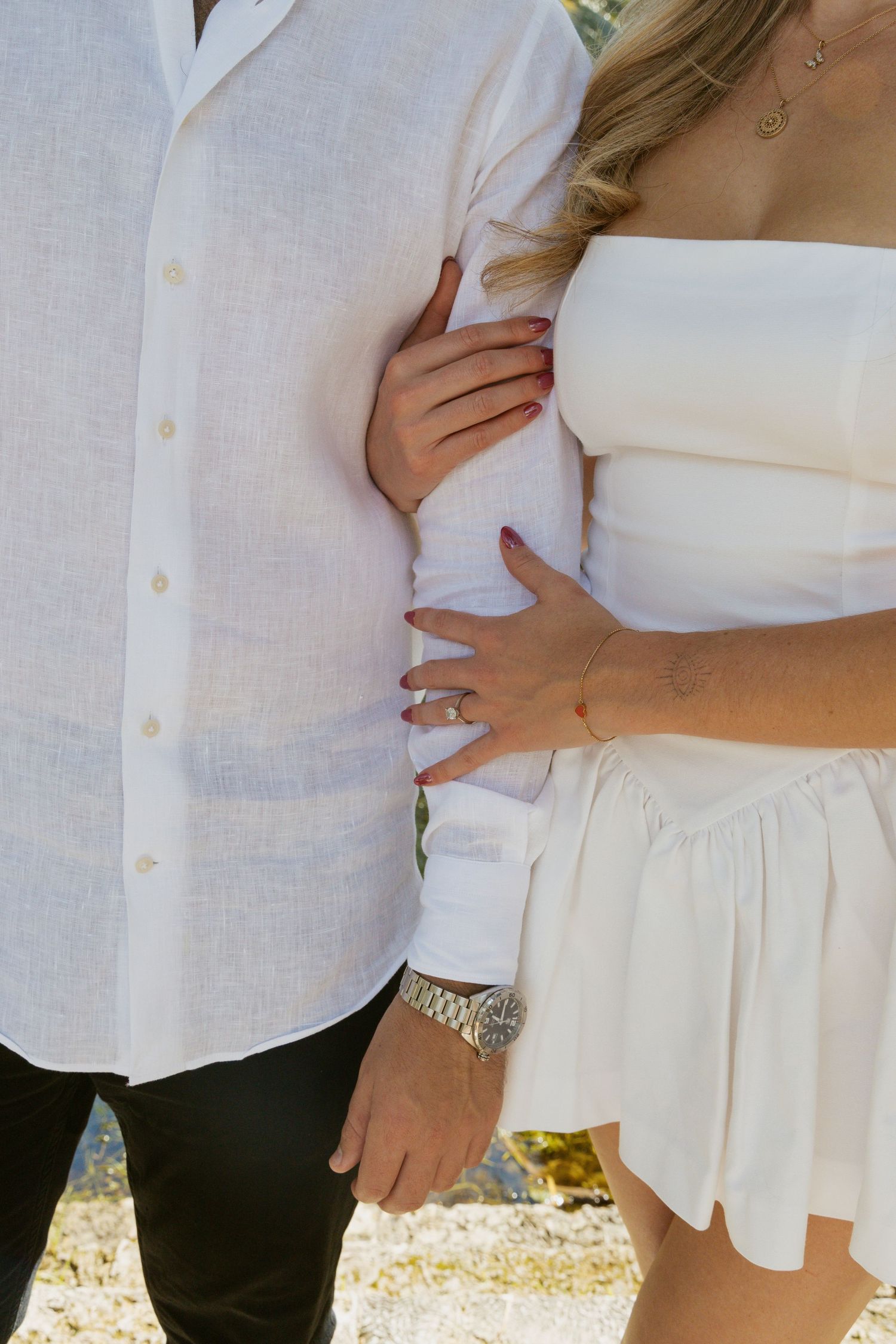 Detail shot of couple's embrace showing white clothing and hands.