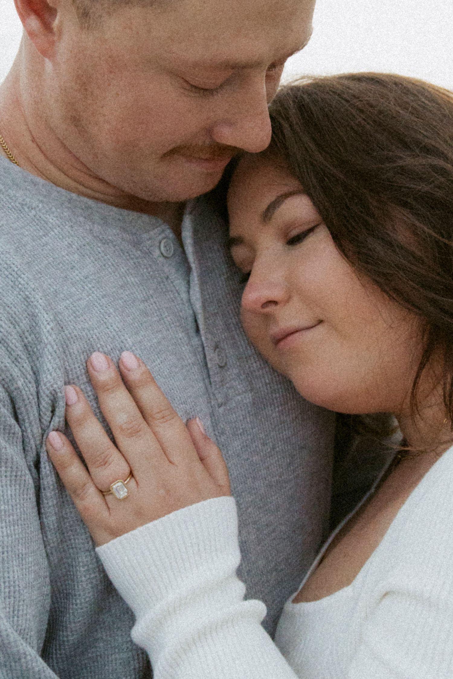 Intimate close-up of couple embracing showing engagement ring.