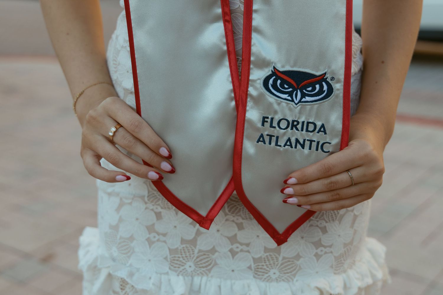 Close-up of Florida Atlantic University graduation attire with owl logo embroidered on white fabric.