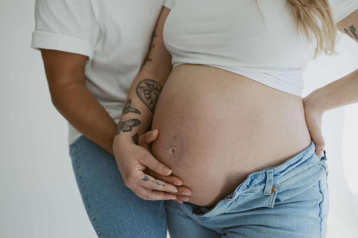 Close-up of pregnant belly with couple's hands tenderly touching the bare bump.