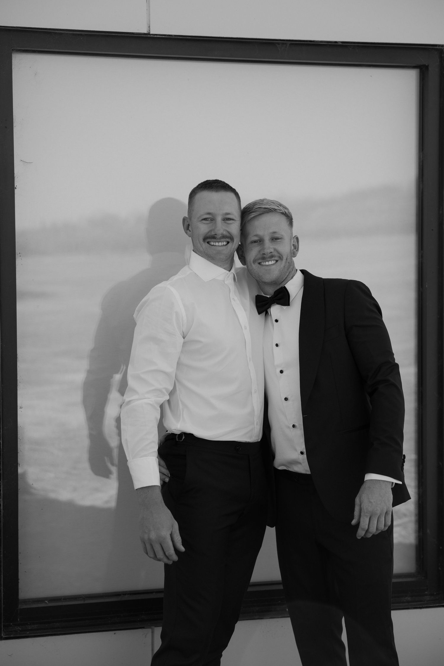 A black and white formal portrait of two people in suits and bow ties.