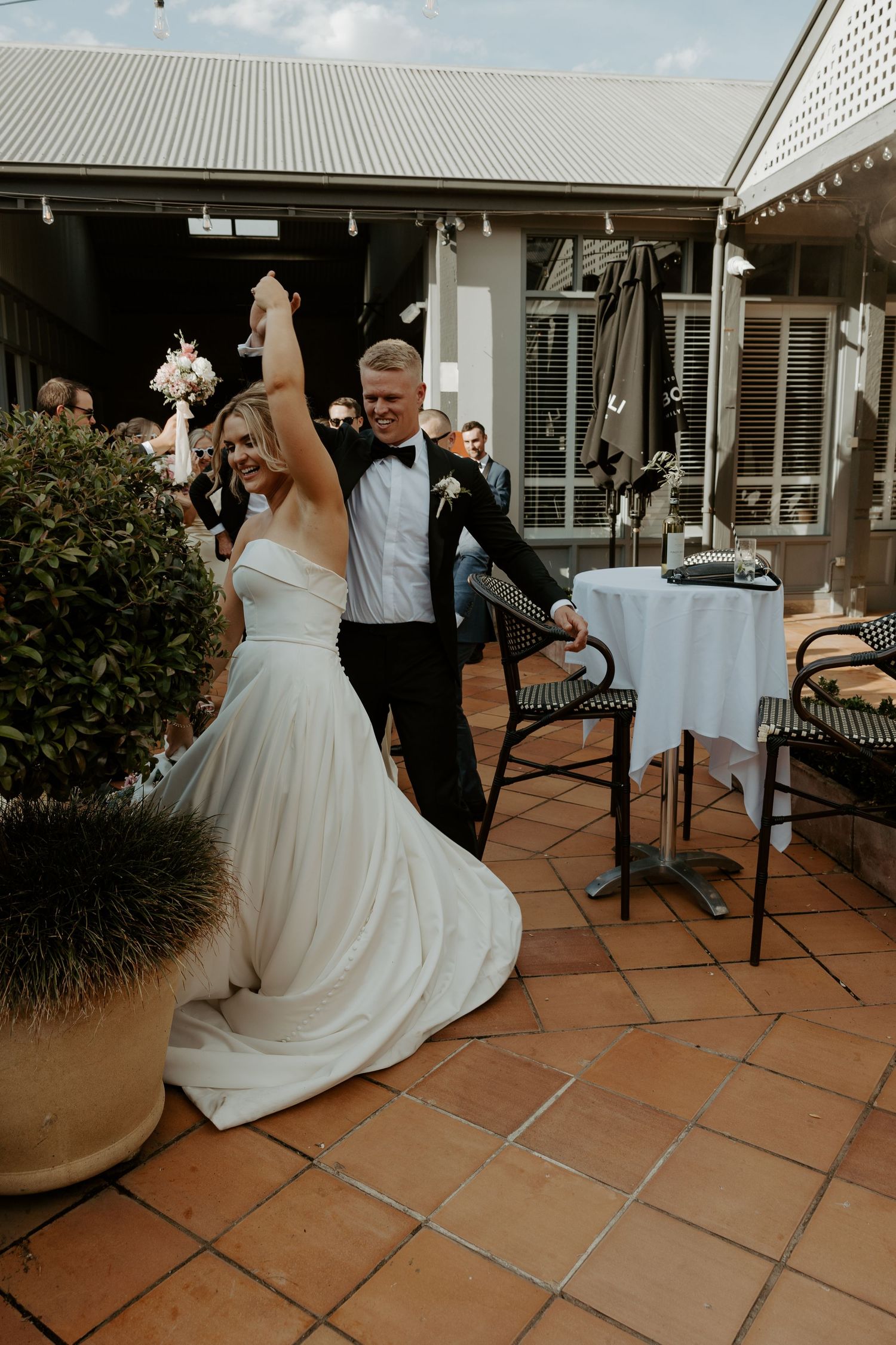 Wedding celebration on outdoor terrace with newlyweds dancing together on terracotta tile patio.