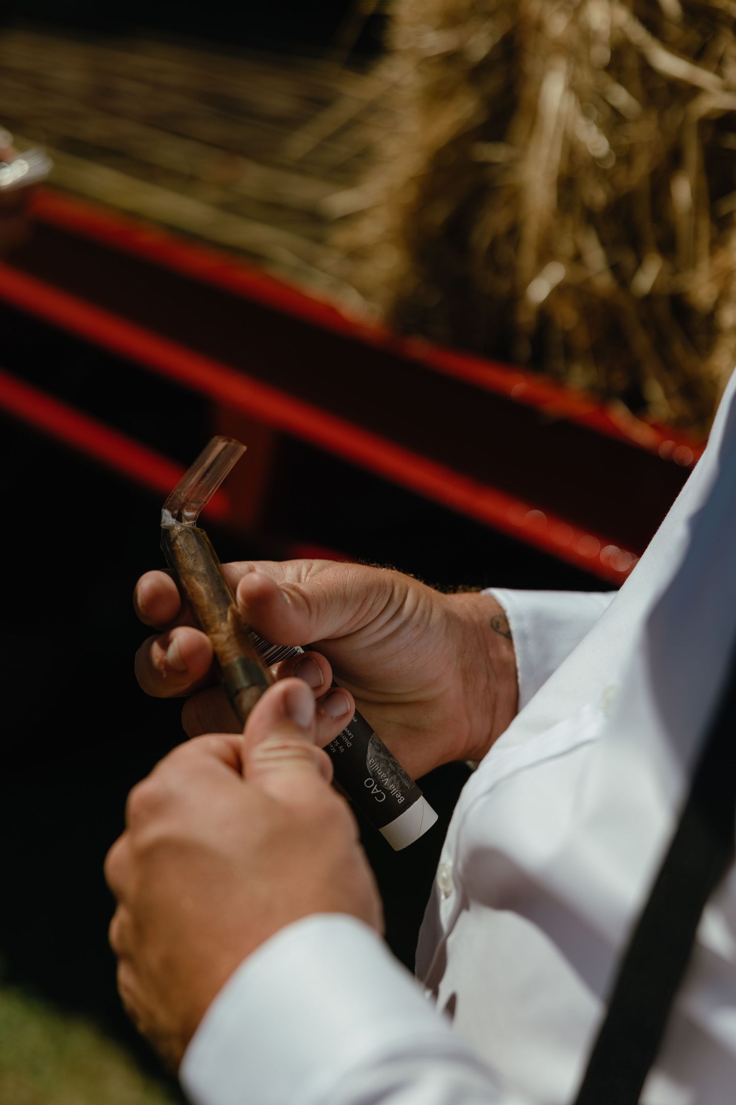 Close-up of hands holding and preparing a cigar at an outdoor event.