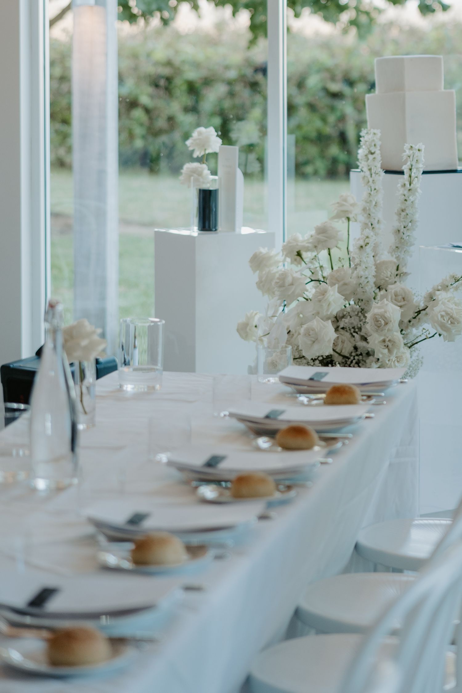 Elegant white dining table set with place settings and delicate floral centerpieces in a bright, airy space.