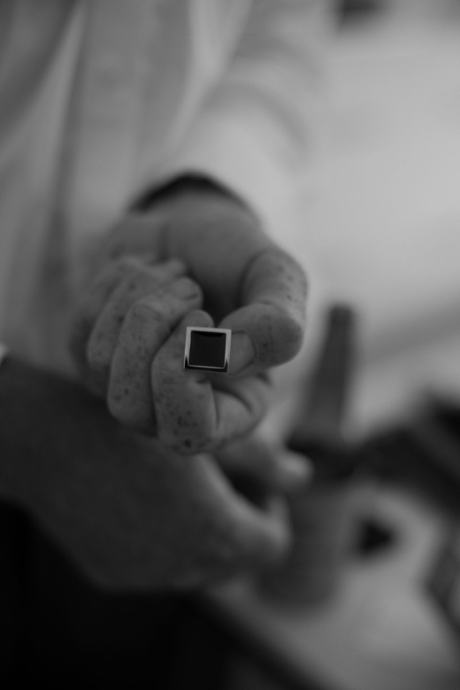A black and white close-up shot of a hand wearing a ring.
