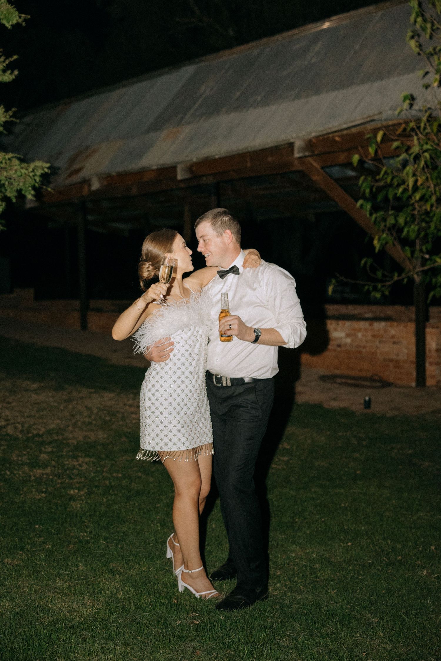Couple sharing a dance together at night under rustic venue lighting.