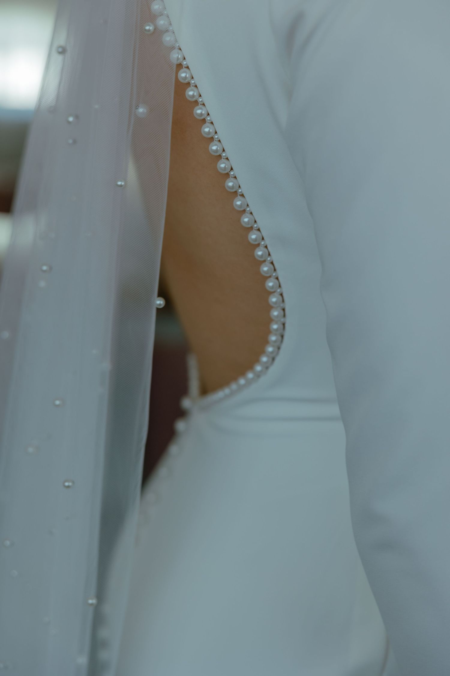 Close-up detail shot of delicate pearl buttons on a white wedding dress.