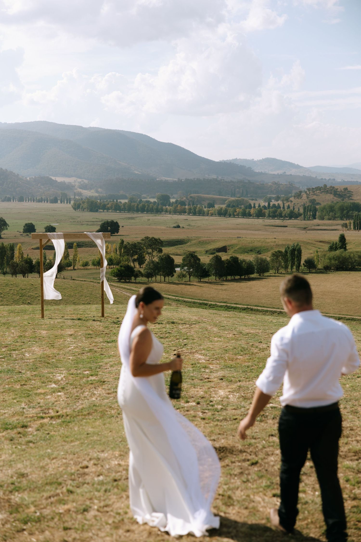 Wedding ceremony on hilltop with scenic mountain valley backdrop.