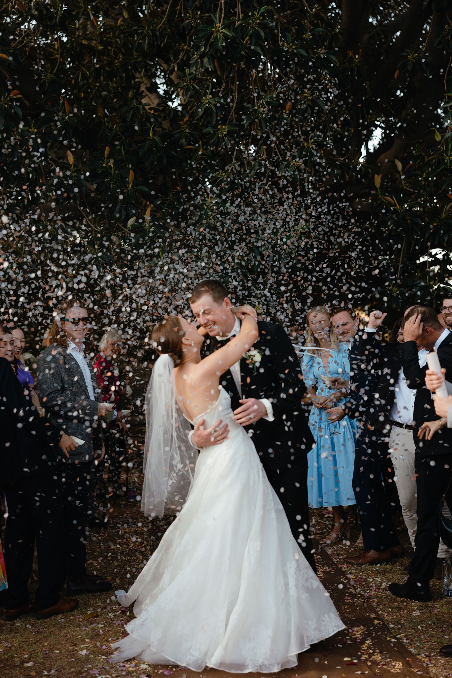Newlyweds sharing a romantic dance moment under a shower of white confetti.