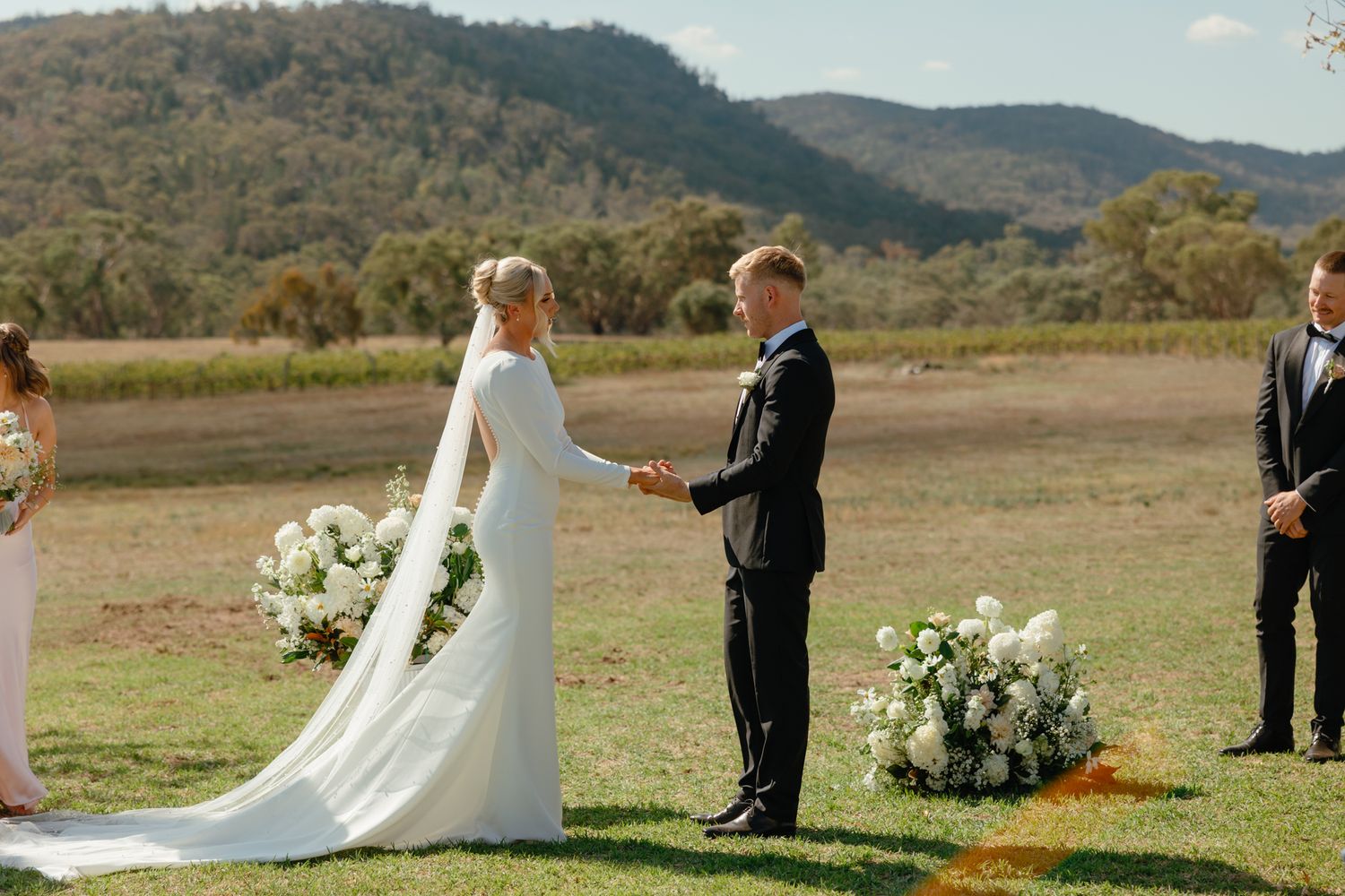 Outdoor wedding ceremony set in a scenic mountain landscape with white floral arrangements along the aisle.