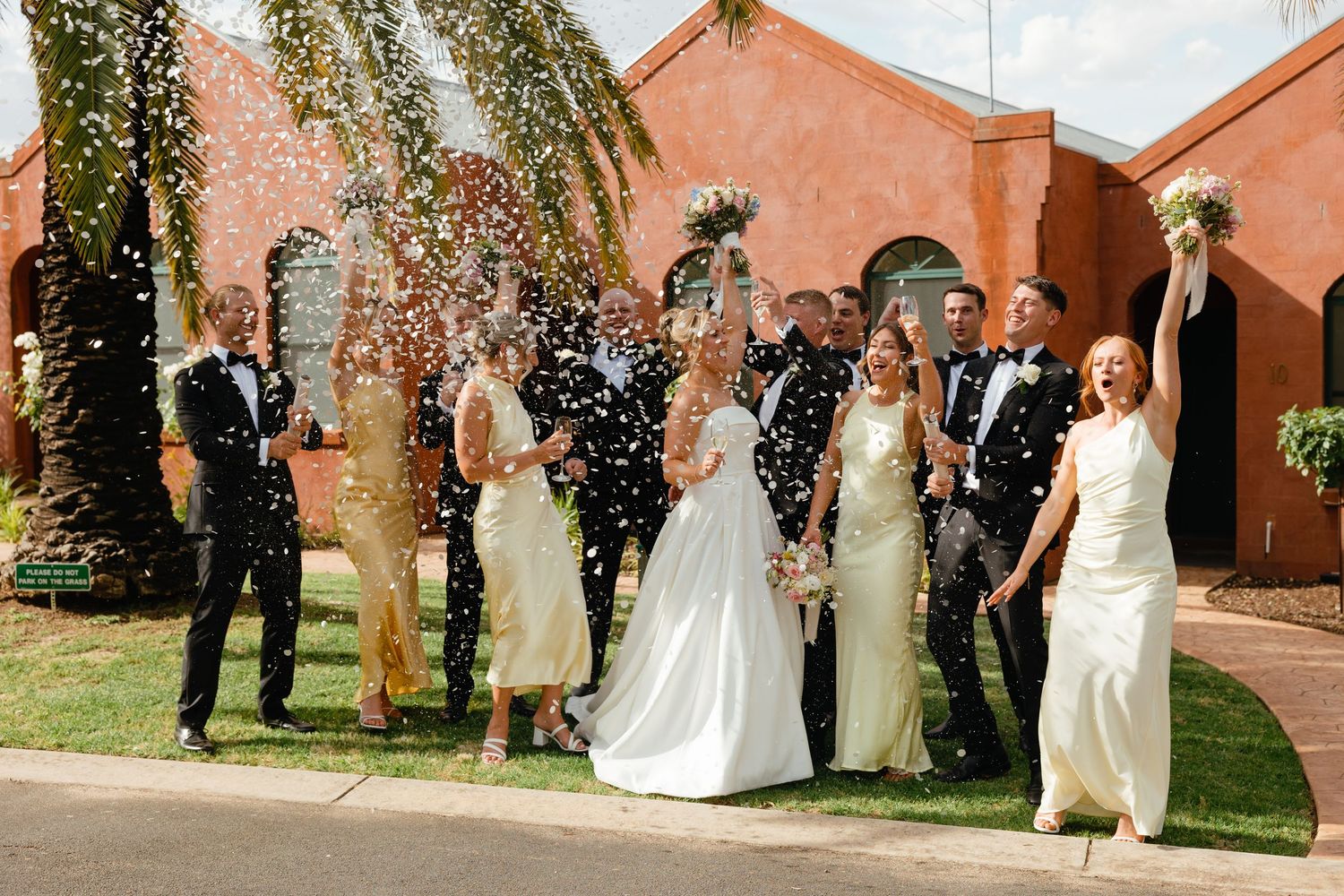 A festive celebration with confetti at an outdoor venue with rustic terracotta walls and greenery.
