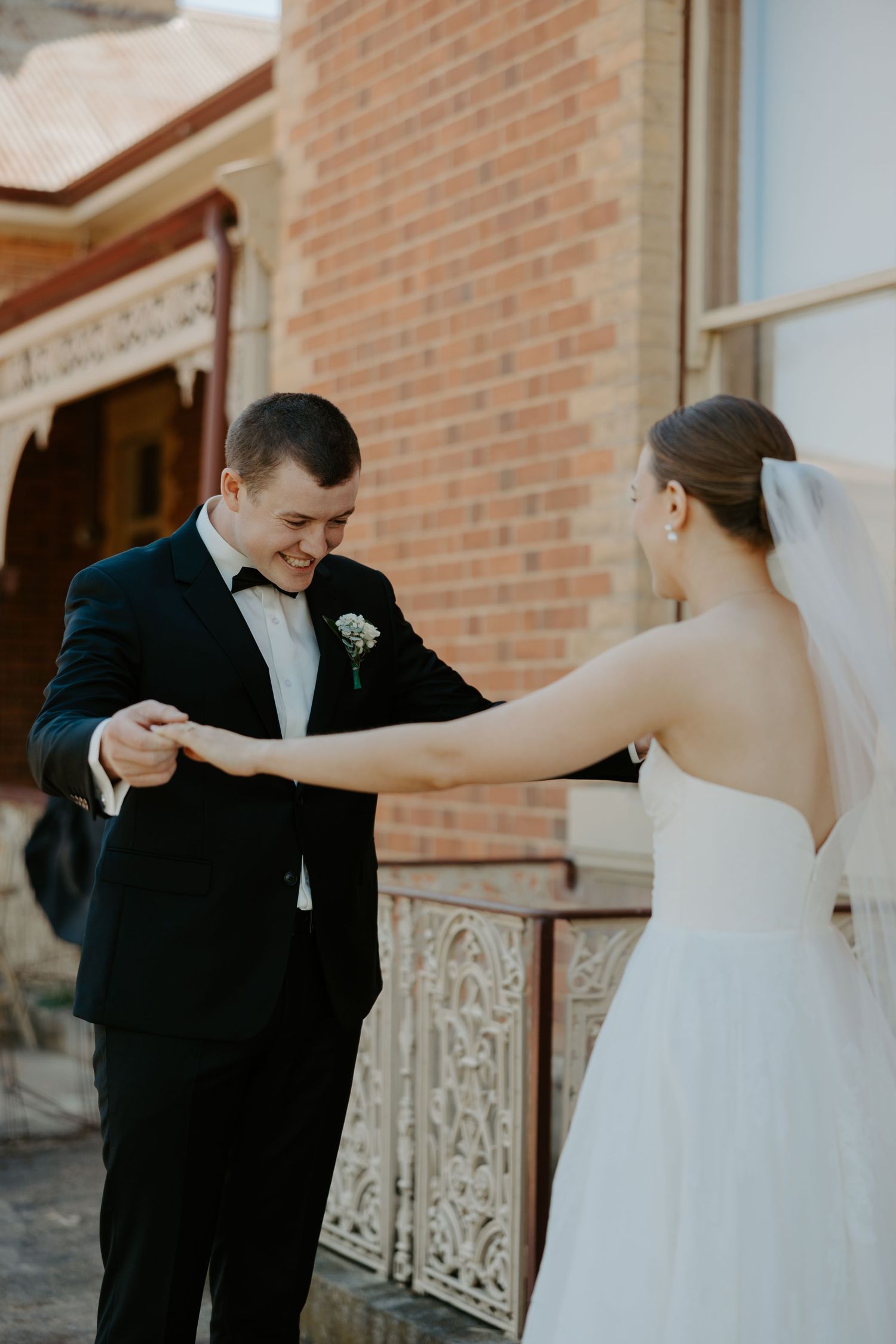 A romantic first look moment between a bride and groom outside a brick building.
