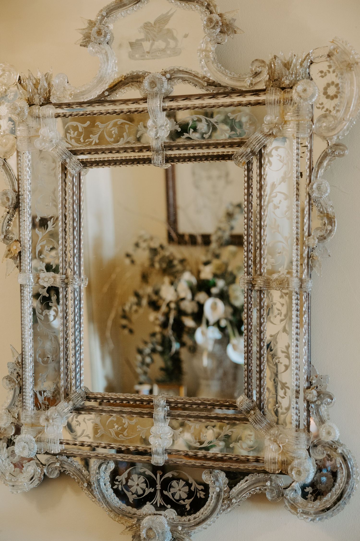 Ornate antique white mirror with baroque-style frame featuring intricate floral details and scrollwork.