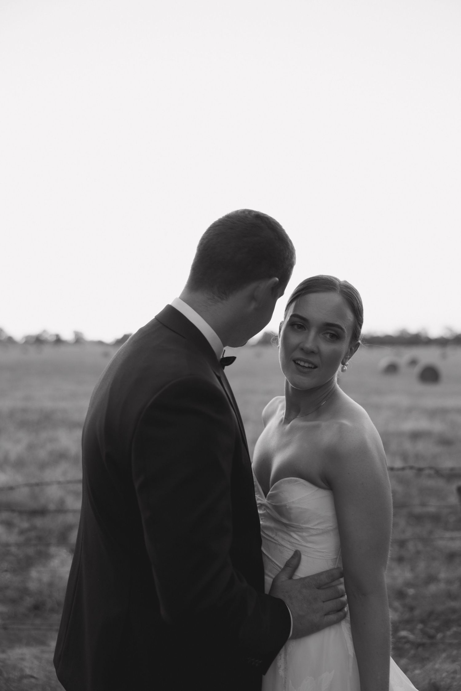 Intimate black and white portrait of newlyweds in a field.