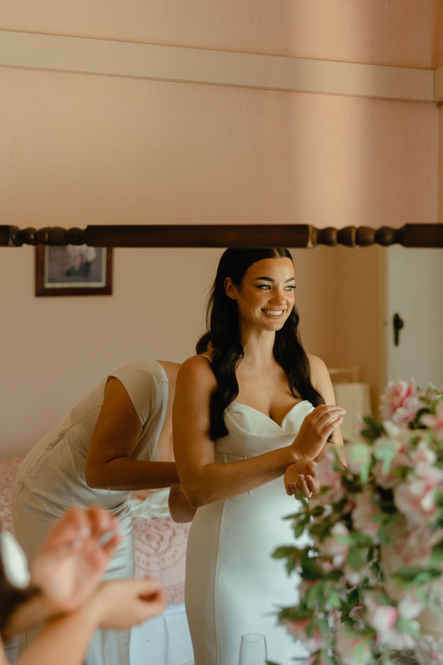 A bride in a sweetheart neckline gown laughs joyfully during wedding preparations.